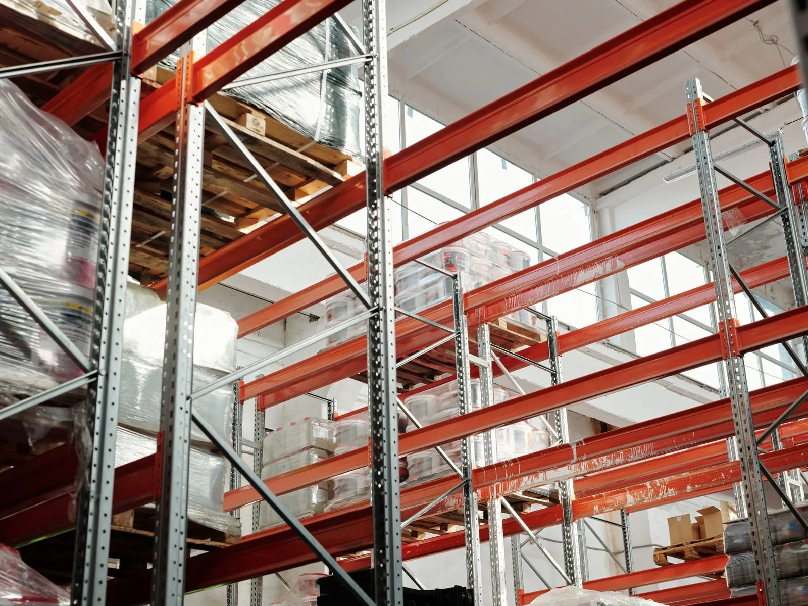 Interior de una bodega logística con estantería industrial y estibas de mercancía