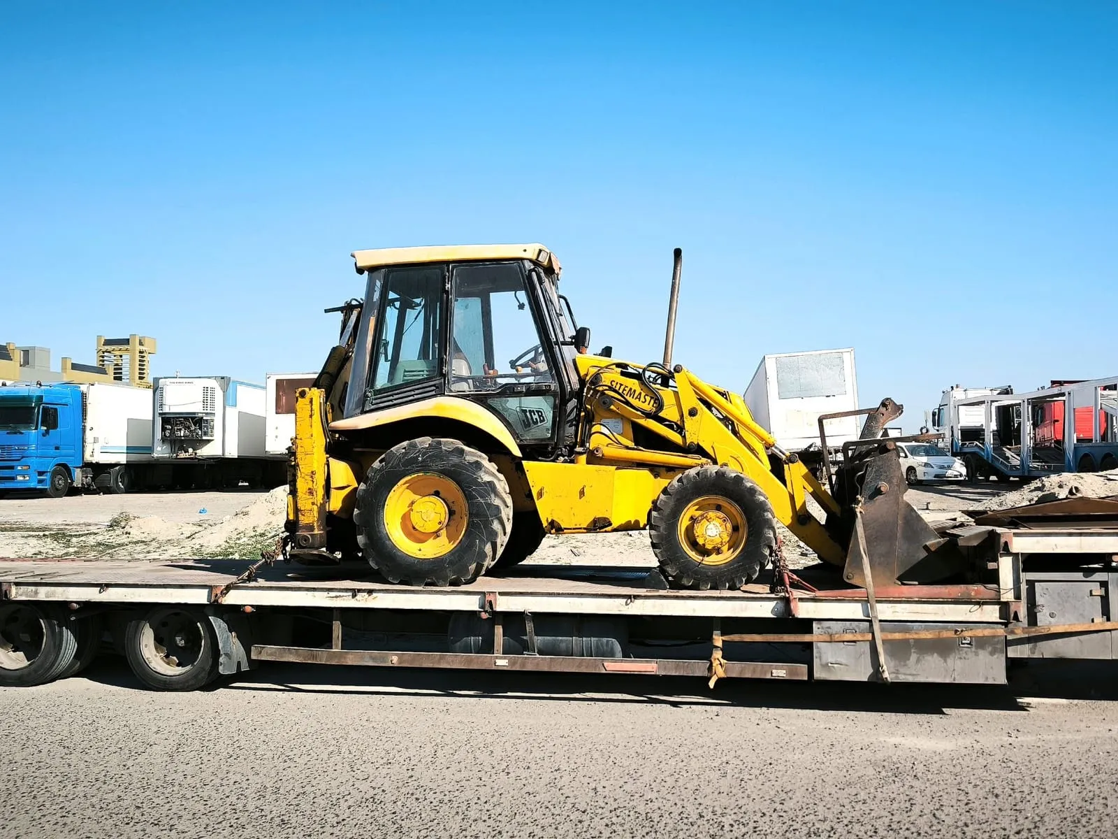 Maquinaria amarilla de construcción asegurada sobre un remolque cama baja